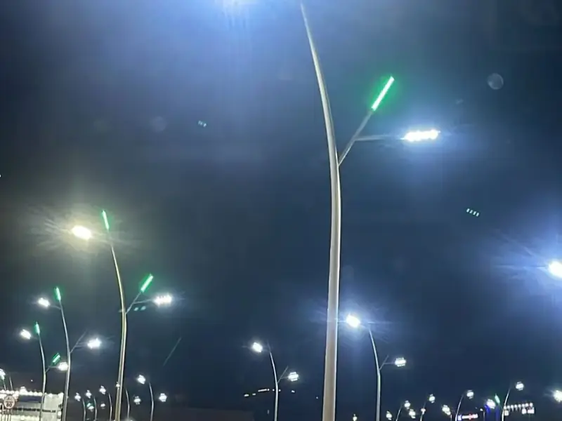أعمدة إنارة ديكورية مخروطية من تنفيذ مصنع أكتار مضاءة ليلاً في مجمع تجاري بأبو عريش