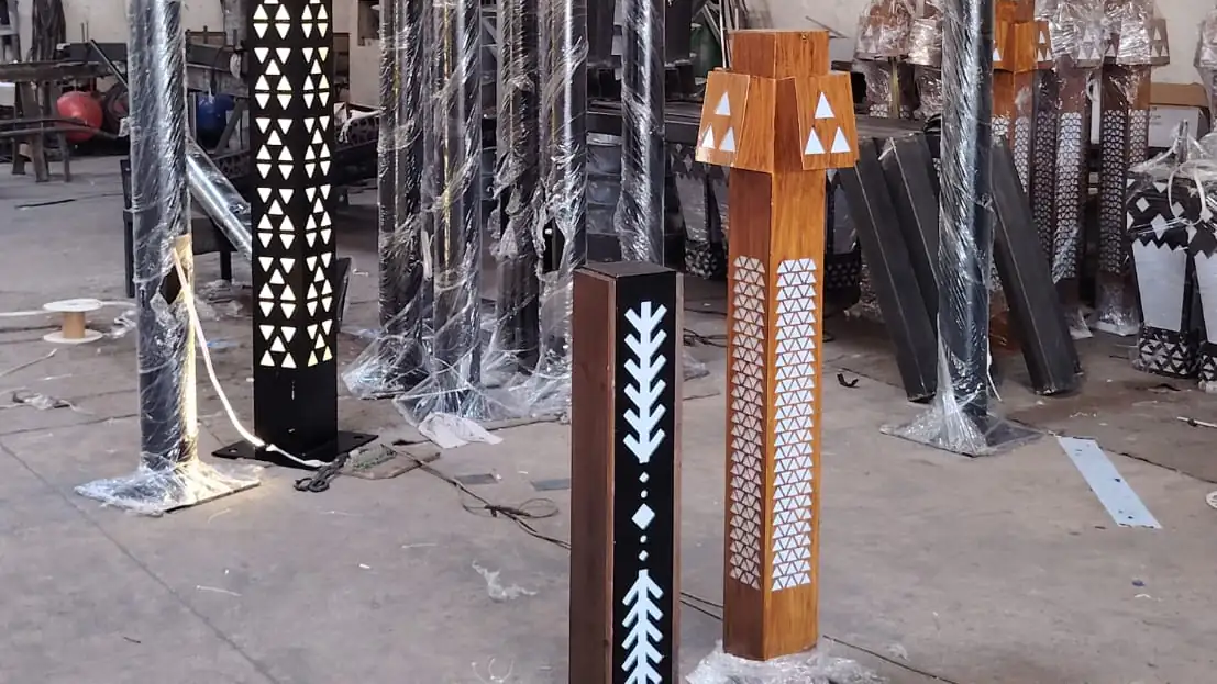 أعمدة إنارة ديكورية بلون خشبي وزخارف مقصوصة بالليزر داخل مصنع أكتار قبل توريدها لمشروع حوطة بني تميم